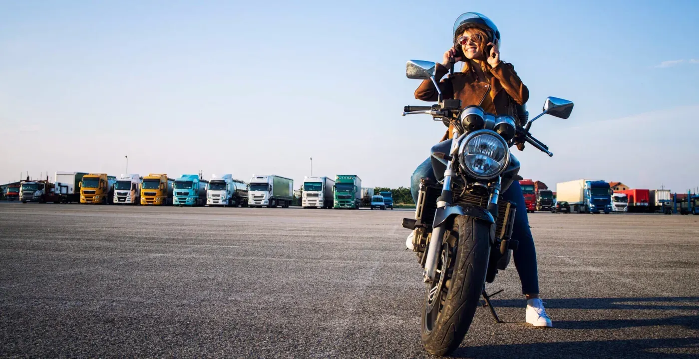 Motorrijdster met helm en motorjas naast haar motor
